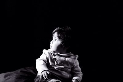 Close-up of cute boy looking away over black background