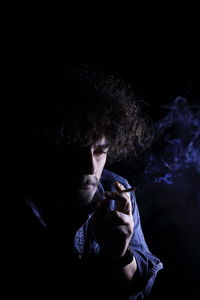 Full length of man smoking against black background