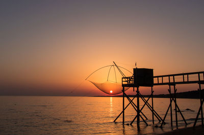 Traditional wooden fishing hut on stilts called fishery by the ocean with a beautiful sunset