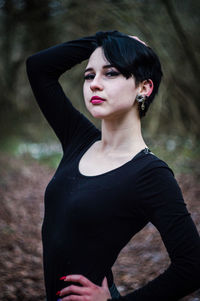 Portrait of woman wearing black dress while standing in forest