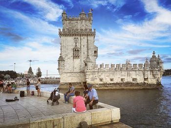 People at historical building against sky