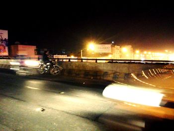 Illuminated street against sky at night