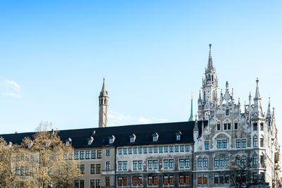 Church by rathausgalerie at marienplatz against blue sky