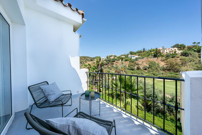 Empty chairs and tables at beach against sky