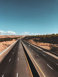 Road passing through landscape against blue sky