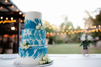 Three tiered white and blue wedding cake with white roses and heart topper.