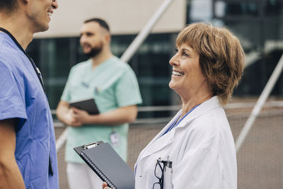 Side view of happy female doctor talking with male colleague