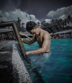 Young man in swimming pool against sky