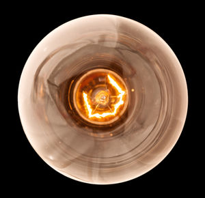 Directly below shot of illuminated light bulb against black background