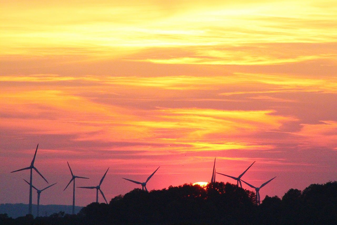 SILHOUETTE OF WIND TURBINES ON LANDSCAPE AGAINST ROMANTIC SKY