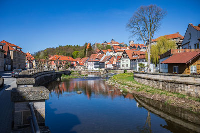 Buildings by river against blue sky