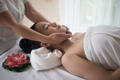 Midsection of therapist massaging young woman in spa