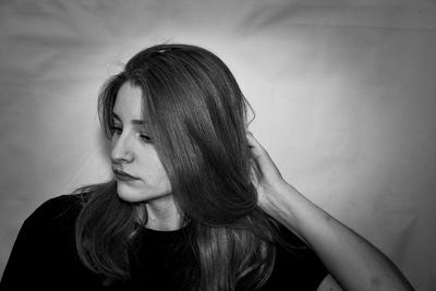 Portrait of young woman looking away against wall