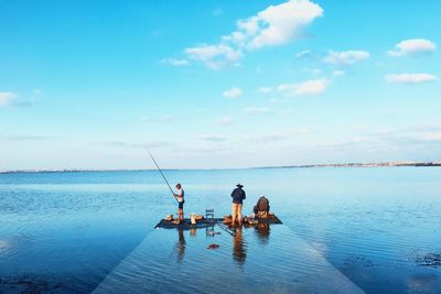 Men fishing at pier against sea