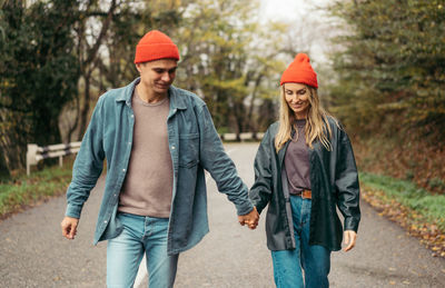 A man and a woman in love walk along the road holding hands.