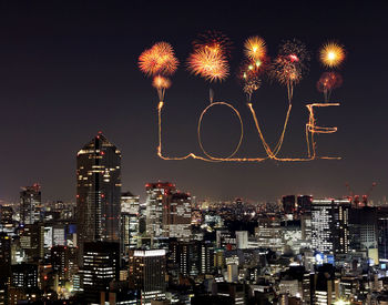 Firework display over illuminated buildings in city at night