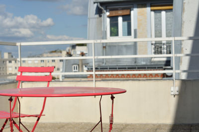 Empty chairs and tables in cafe against buildings in city