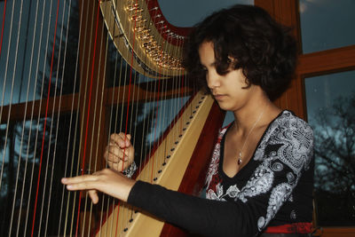 Woman playing harp at home