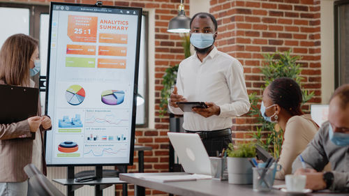 Businessman wearing mask giving presentation at office