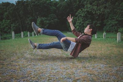 Side view of young man jumping on field