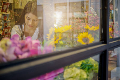 Woman looking at flowers seen through shop window