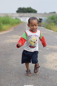 Full length of innocent boy running on road