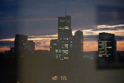 Illuminated buildings in city against sky during sunset