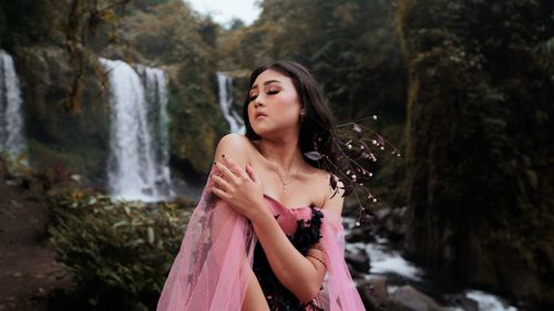 Beautiful young woman looking at waterfall
