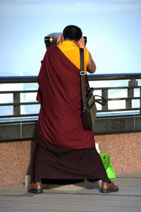 Monk glimpse city through binoculars