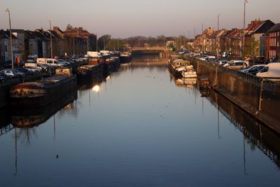 Boats moored in harbor against buildings in city