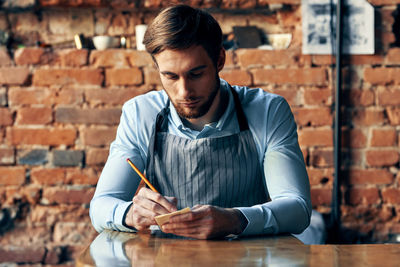 Young man looking away while sitting on table