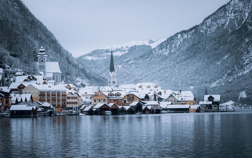 Houses by snowcapped mountains against sky during winter