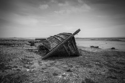 Abandoned boat on shore against sky