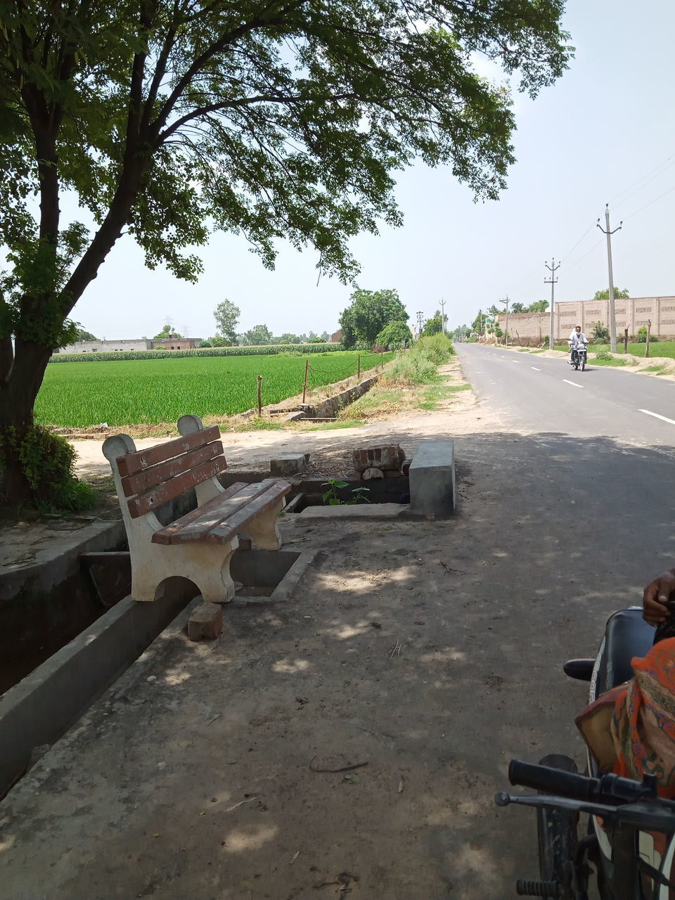 EMPTY BENCHES BY ROAD AGAINST SKY