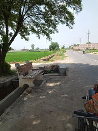 Empty bench by road against clear sky