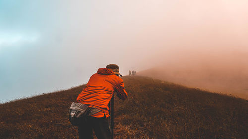 Man standing on field against sky during sunset