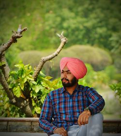 Thoughtful young man wearing turban sitting in park