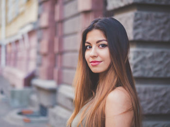 Portrait of woman standing against wall