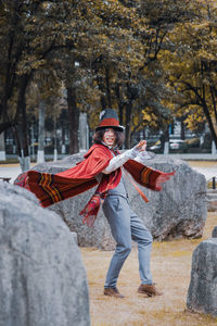 Full length portrait of happy man spinning around stones by tree