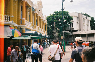 People walking on street amidst buildings in city