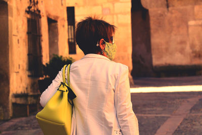 Rear view of woman standing against building in city