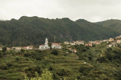Houses by trees and mountains against sky