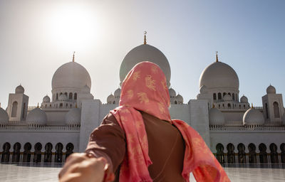 Cropped image of man holding woman hand at sheikh zayed mosque during sunny day
