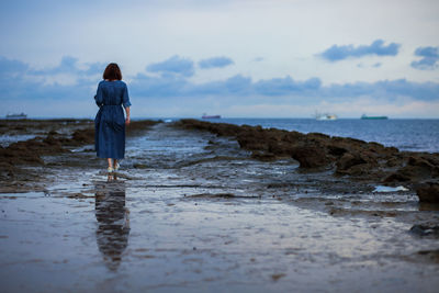 Rear view of woman standing on beach