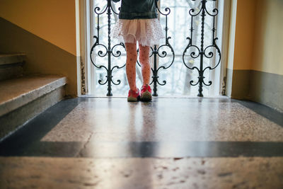 Low section of girl standing by window in corridor