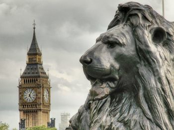 Close-up of lion sculpture with big ben in background against sky