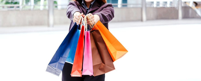 Midsection of woman holding multi colored umbrella