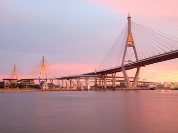 View of suspension bridge over river at sunset