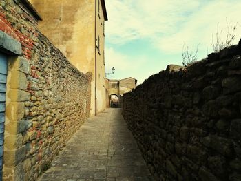 Walkway amidst buildings against sky