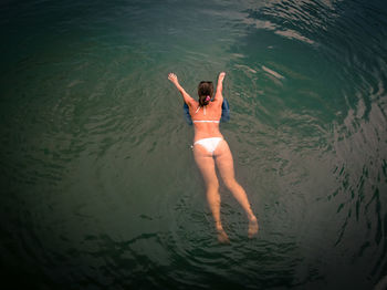 High angle view of young woman wearing white bikini swimming in lake